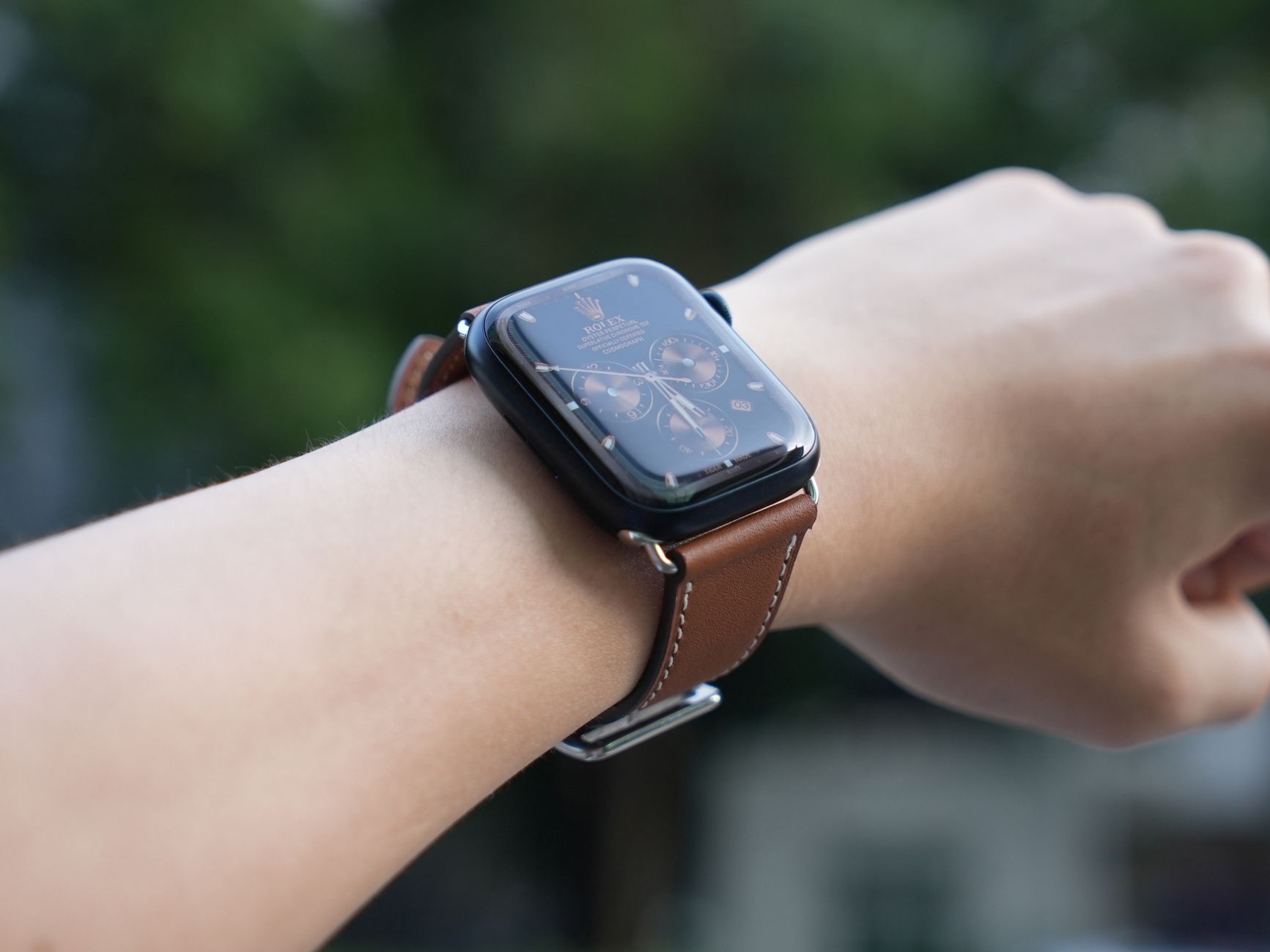 Elegant wristwatch with brown leather strap worn on a wrist outdoors.