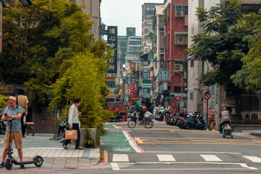 Bustling city street with people, cyclists, scooters, and vibrant urban elements.