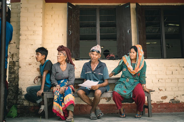 People In Traditional Indian Clothing Sitting On A Bench