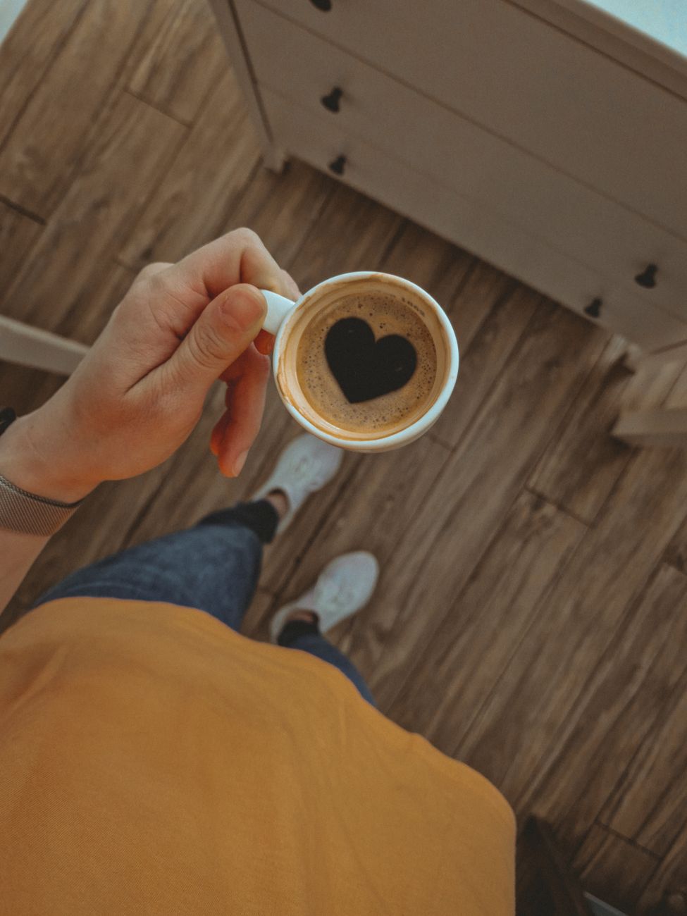 Overhead shot of a coffee cup with heart-shaped foam held by a person in a cozy setting.. pexels, overhead, shot