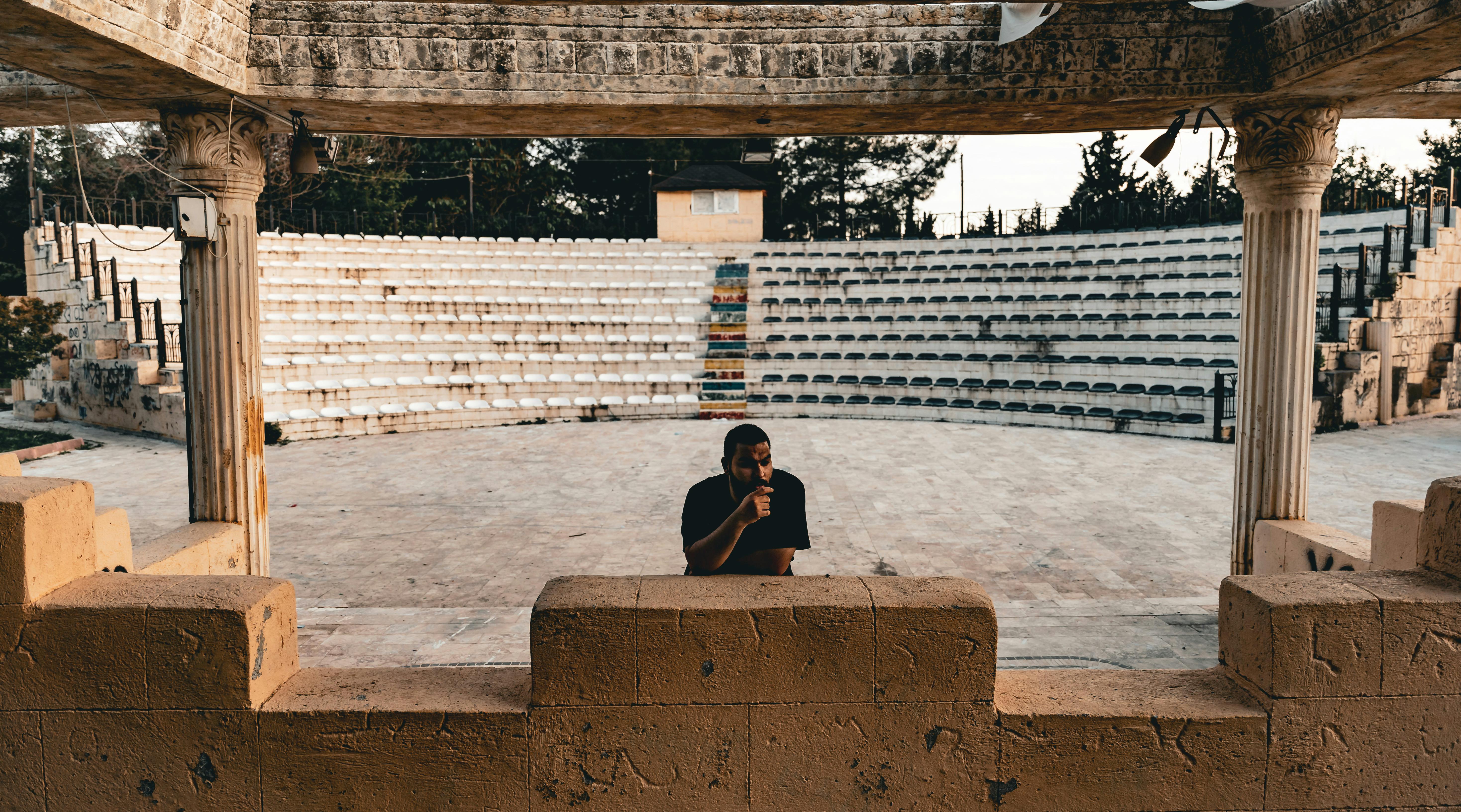 Free Man standing alone in an ancient amphitheater, capturing historical ambiance. Stock Photo