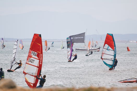 Energetic scene of windsurfers racing with colorful sails on open sea.