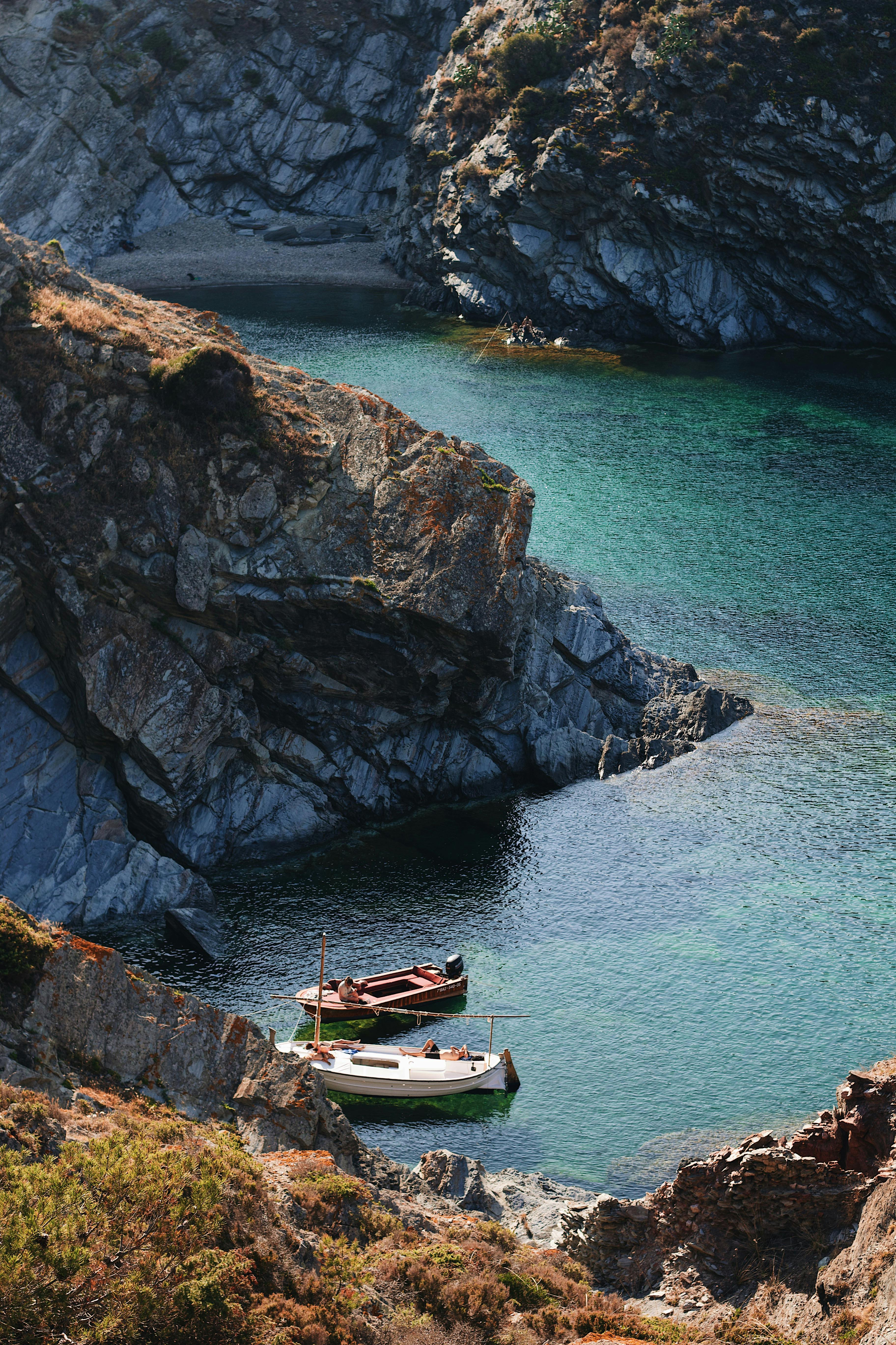 Beautiful secluded cove with clear turquoise waters, rocky cliffs, and small boats.