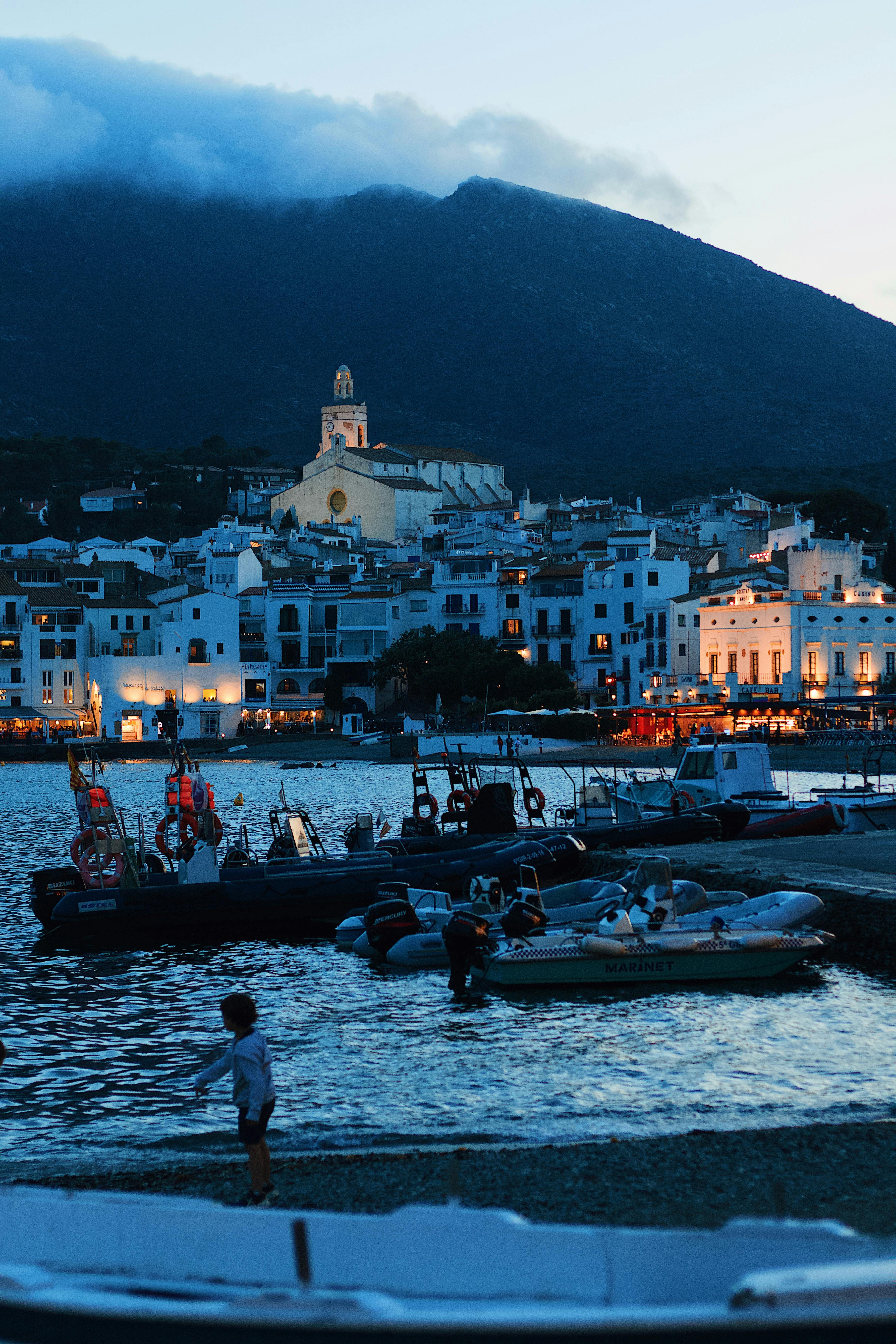 Scenic evening view of a harbor with boats docked in a picturesque coastal town.