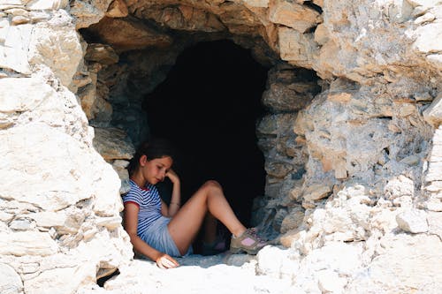 A girl sitting in a cave with a phone