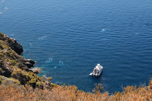 A boat is sailing on the water near a cliff