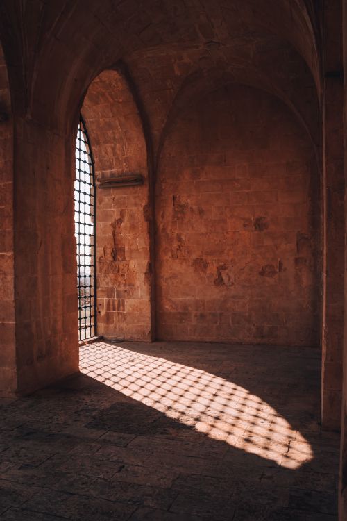 Free Sunlight casts geometric shadows through an arched doorway in Mardin's historic architecture. Stock Photo