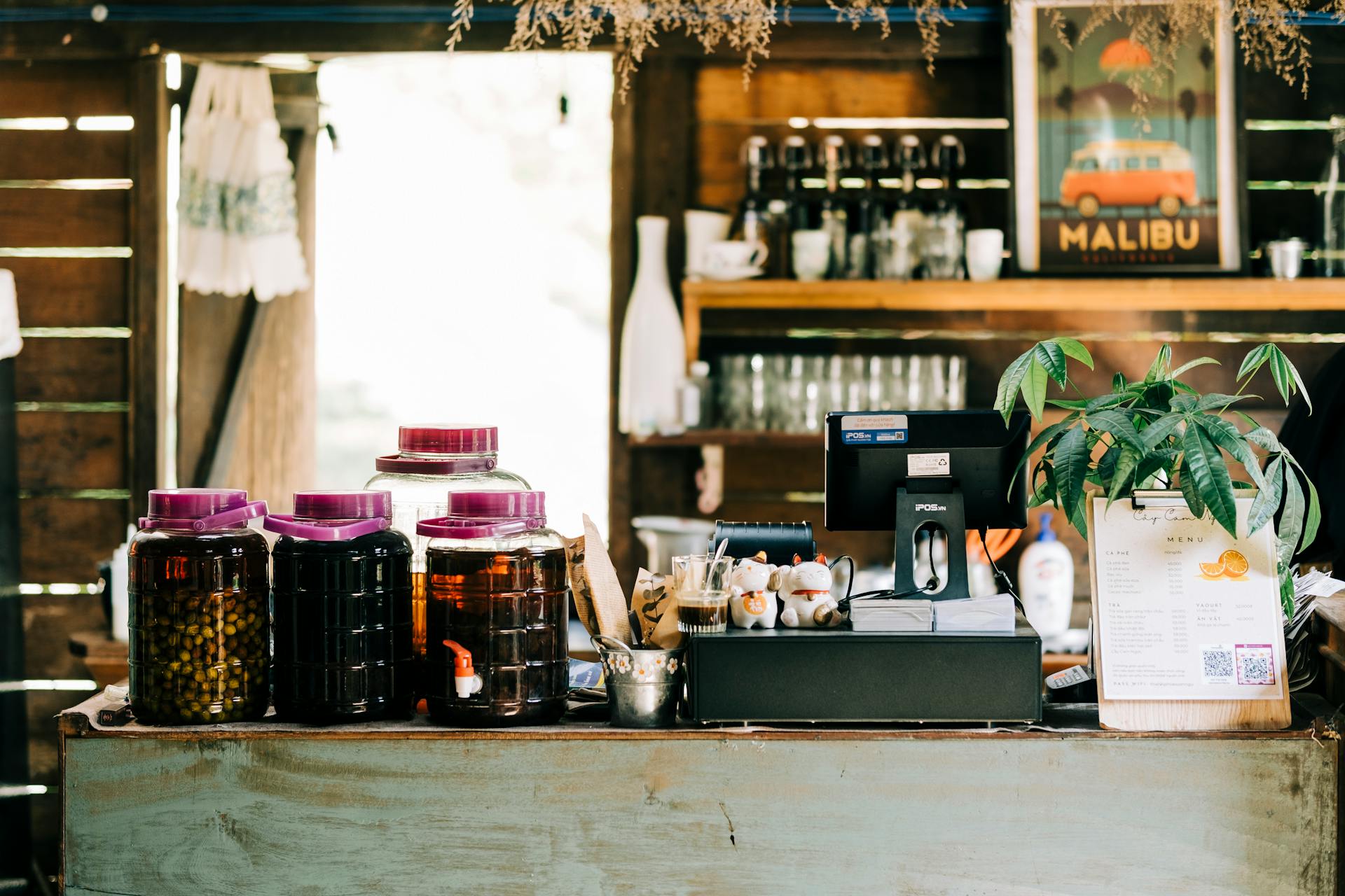 A rustic bar counter with jars, decor, and a POS system in a cozy setting.