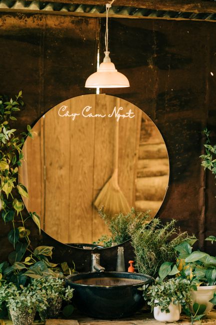 Rustic bathroom with round mirror, hanging lamp, and potted plants for a fresh and natural look.