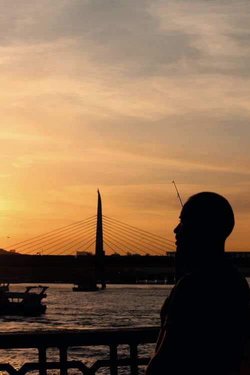 Free A man's silhouette against the backdrop of a bridge and sunset in Istanbul. Stock Photo