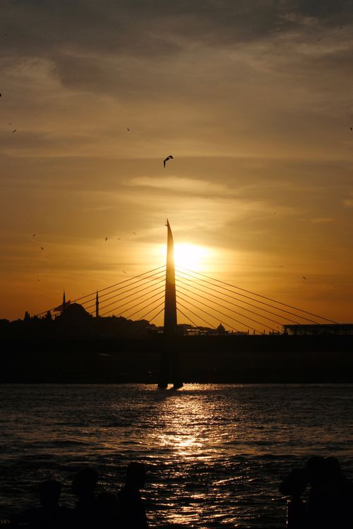 Free Silhouette of Istanbul's skyline with a bridge at sunset, featuring a dramatic sky and reflections in the water. Stock Photo