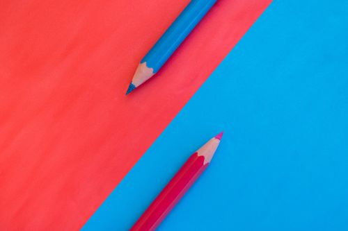 Free A vibrant and minimalistic composition with red and blue pencils on contrasting backgrounds. Stock Photo