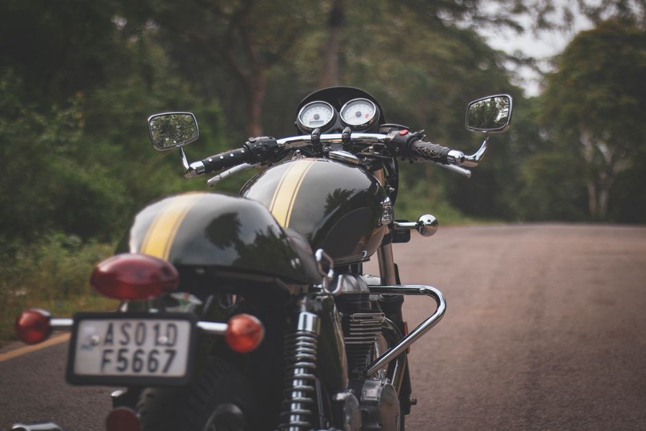 A classic cafe racer motorcycle parked on a tree-lined road, perfect for adventure enthusiasts.