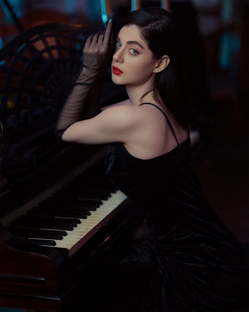 Woman in Black Dress Sitting by Piano