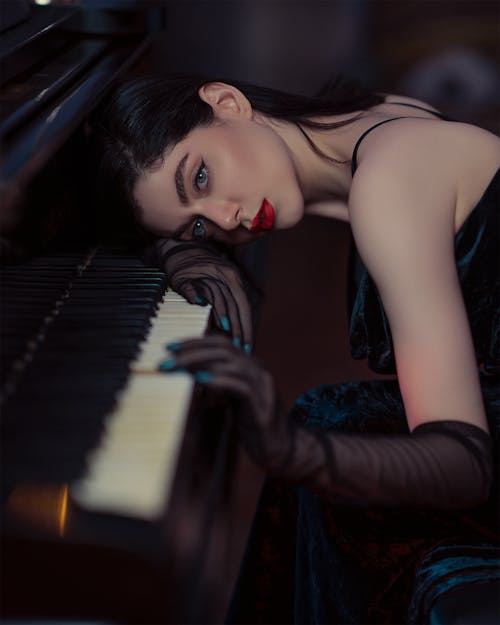 Free Woman in Evening Dress Lying on Piano Stock Photo