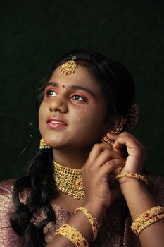 A woman in traditional attire and jewelry looks upwards, showcasing cultural elegance.