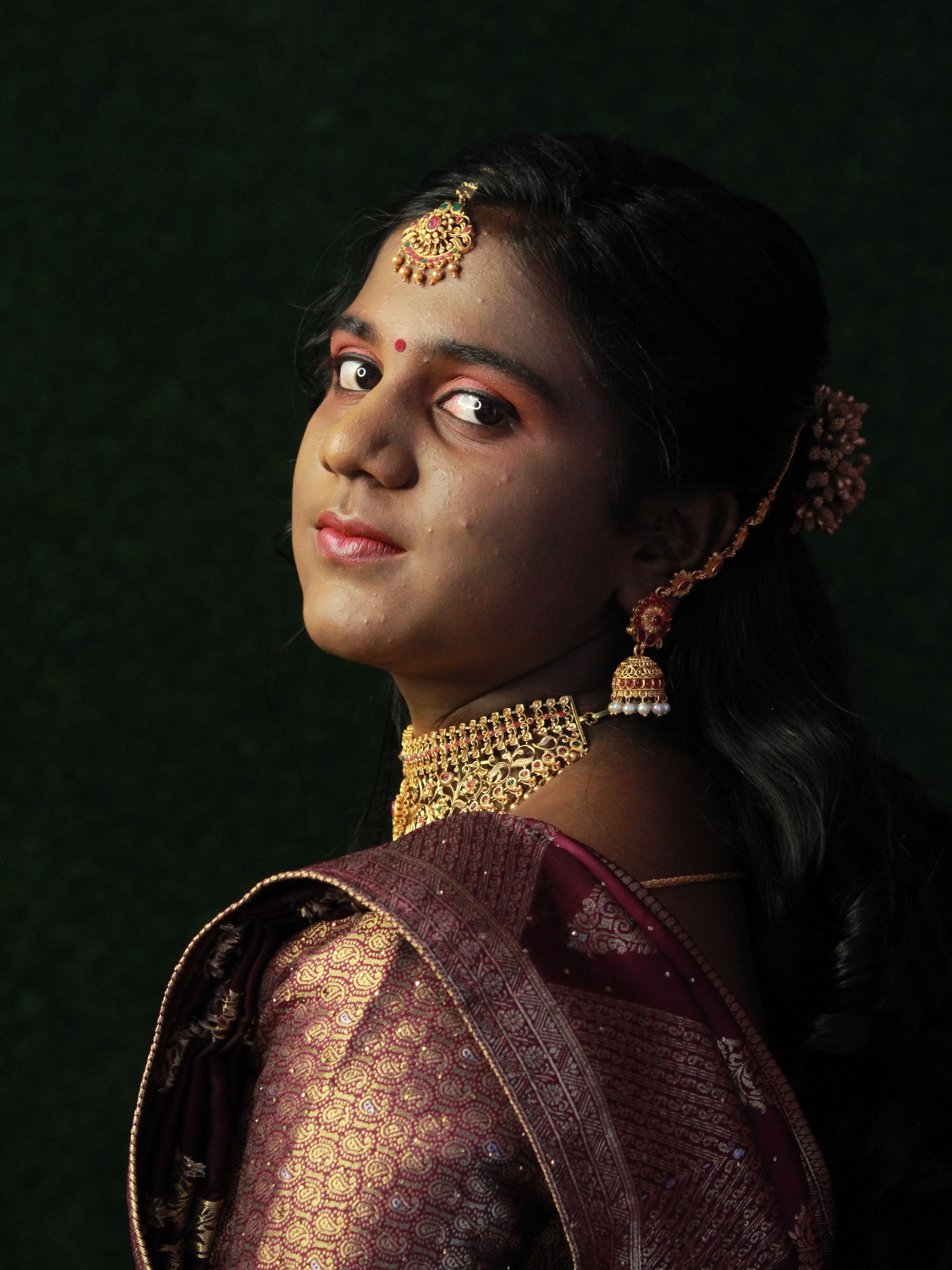 Portrait of a woman in ornate traditional attire with jewelry and elegant makeup.