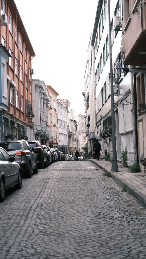 Free A quiet cobblestone street lined with parked cars and historic buildings in Istanbul, Turkey. Stock Photo