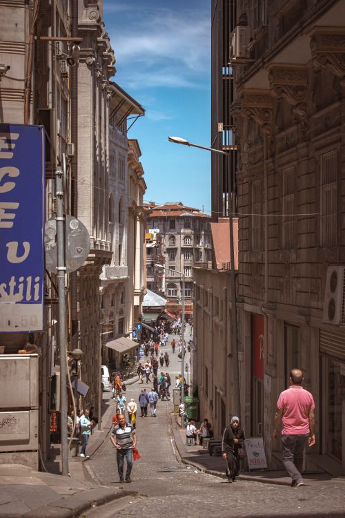 Free Urban street scene with people walking between historic buildings on a sunny day. Stock Photo