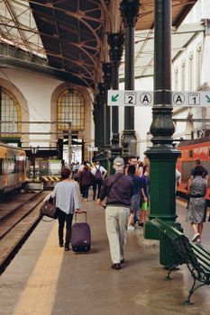 Passengers walking at São Bento train station in Porto, showcasing architectural elegance.