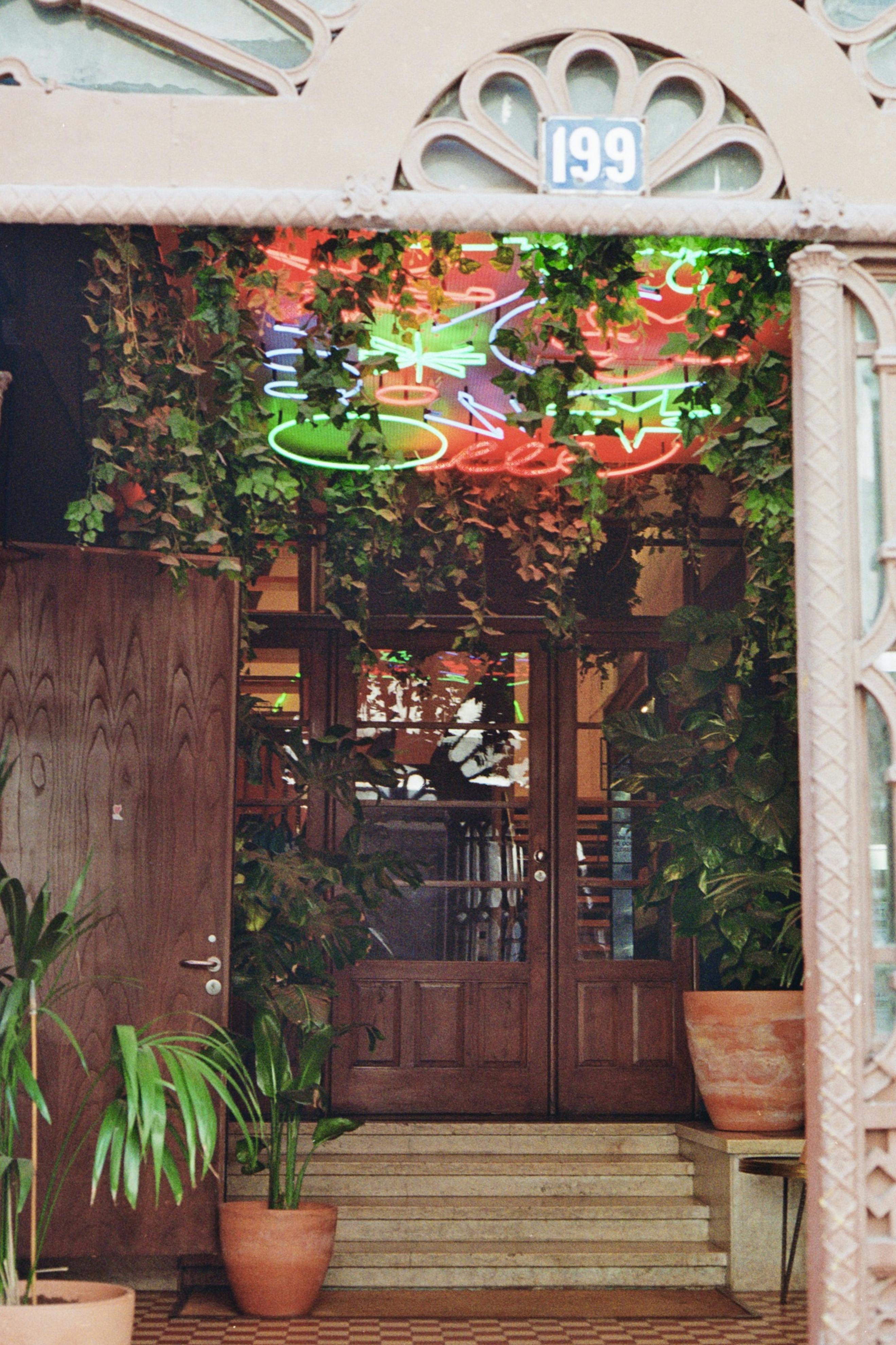 A neon sign is hanging from the entrance of a building · Free Stock Photo
