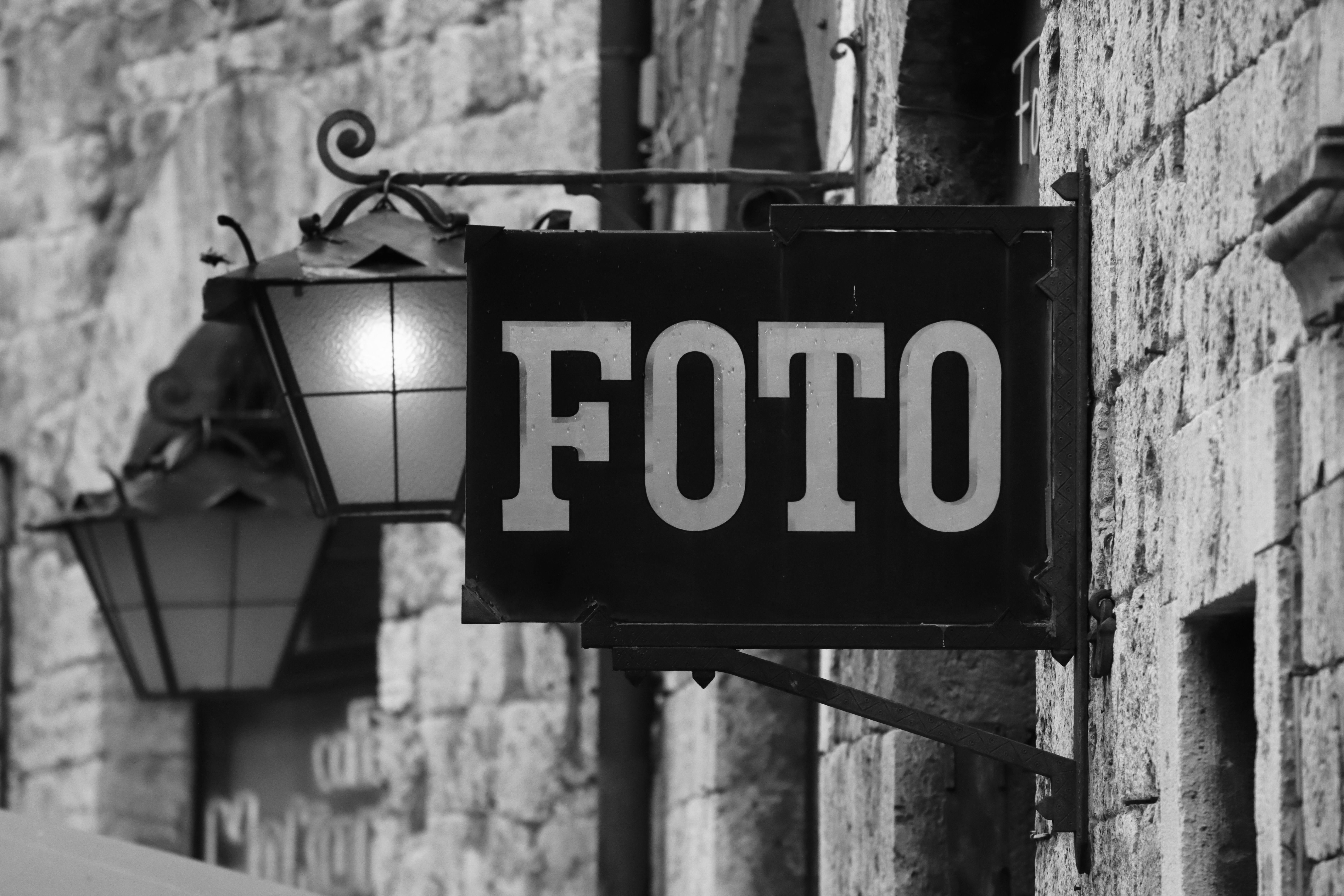Close-up shot of a vintage 'Foto' sign with old stone walls in Florence, Italy.