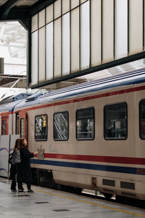 Free Commuters standing alongside a passenger train at an urban railway station. Stock Photo