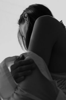 A black and white artistic portrait showcasing a woman in a sensual, introspective pose.