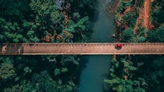 从令人惊叹的鸟瞰视角看去，一辆汽车正驶过菲律宾诺扎加雷市一座横跨河流的桥，四周环绕着郁郁葱葱的森林