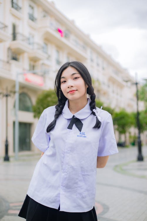 Young Girl in a School Uniform Standing Outside in City 