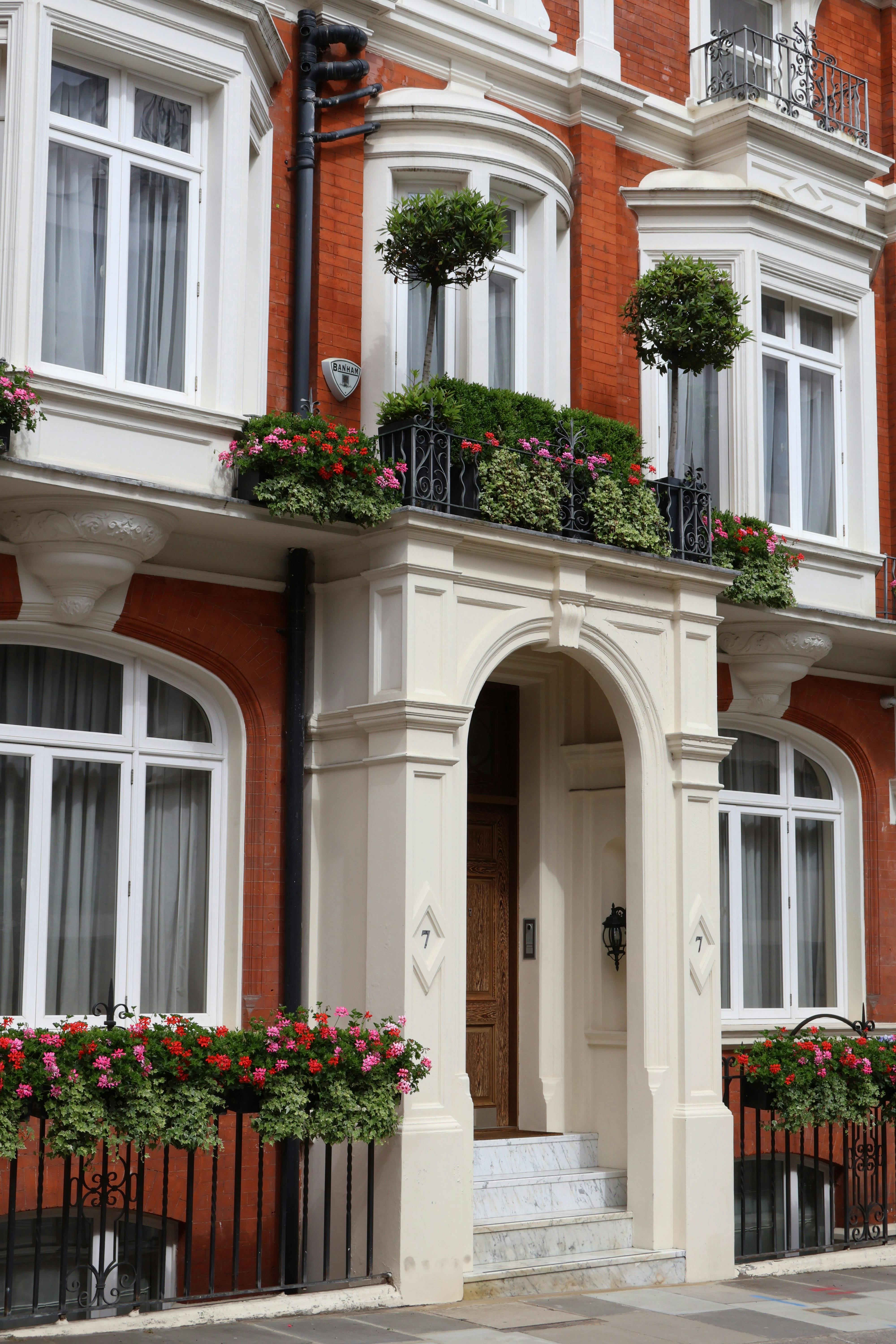 Elegant facade of a London building with colorful flowers on balconies and classic architecture.