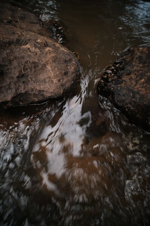 Free A mesmerizing view of water flowing between rocks, highlighting natural textures and motion. Stock Photo