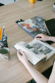 A woman reads a book at her desk with coffee and pencils nearby, creating a cozy study environment.