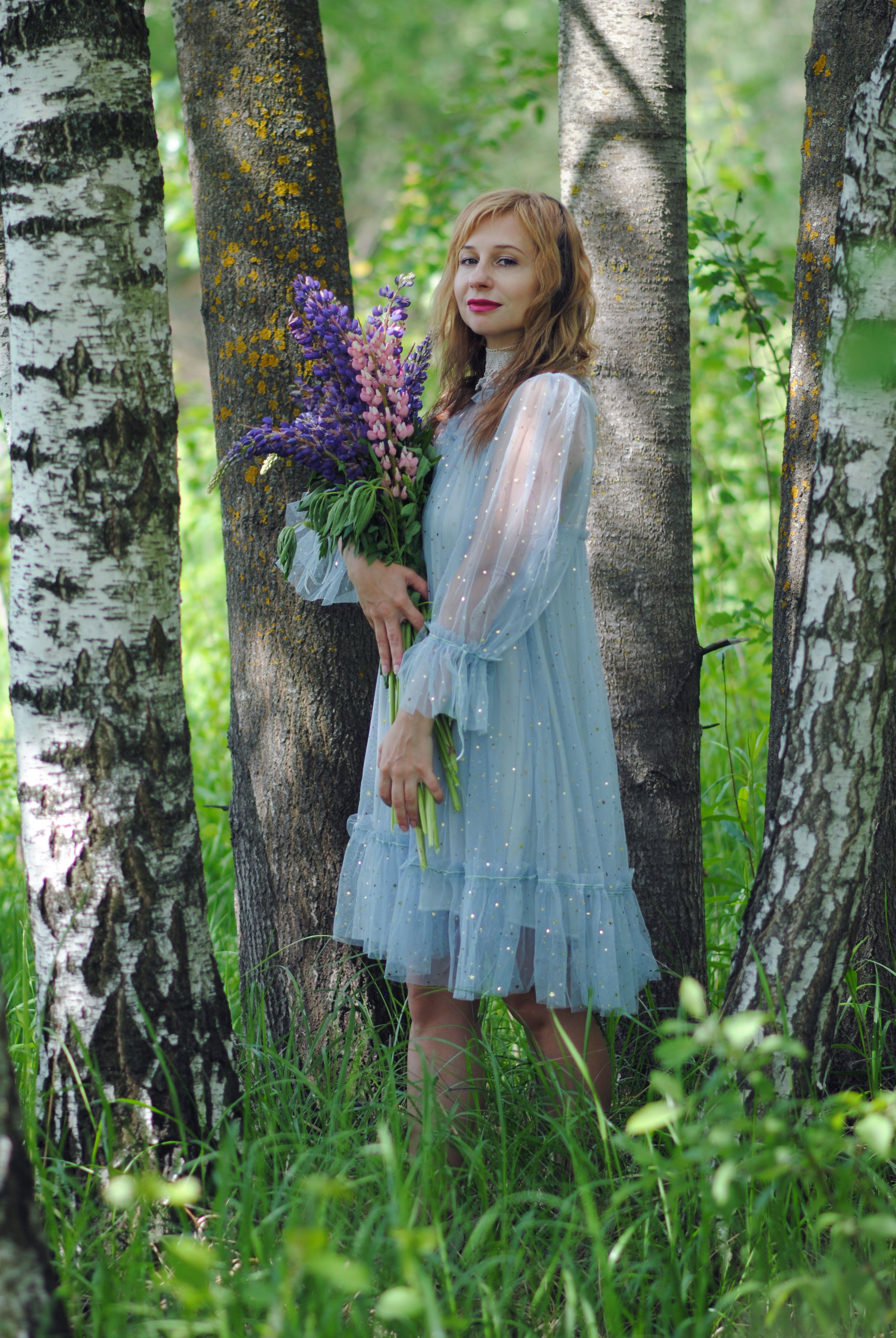 Young Woman in a Dress Standing Outside and Holding a Bunch of Purple ...