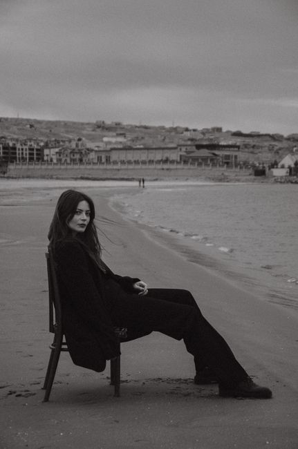 Black and white portrait of a woman sitting on a chair by the beach in Baku, Azerbaijan.