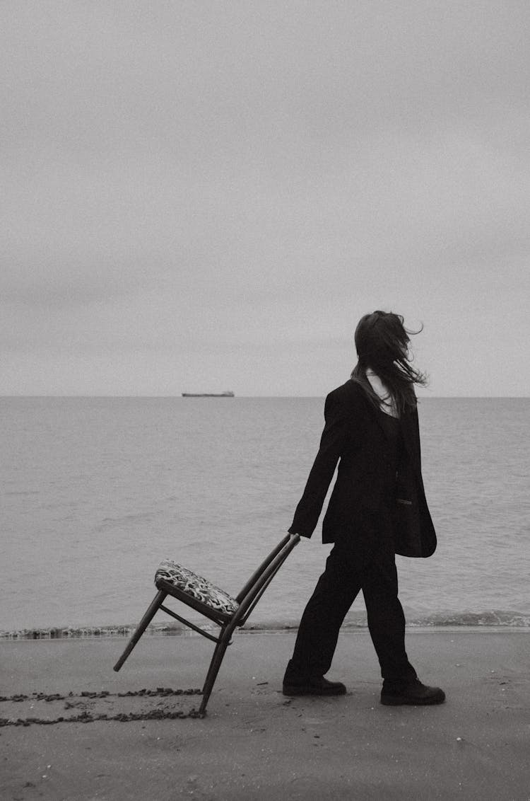 Woman Pulling Chair On Beach