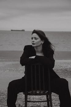 Monochrome portrait of a woman posing on a chair at the beach.