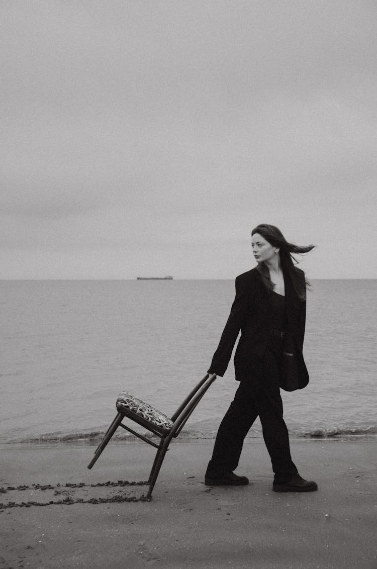 Woman Pulling Chair On Sandy Beach