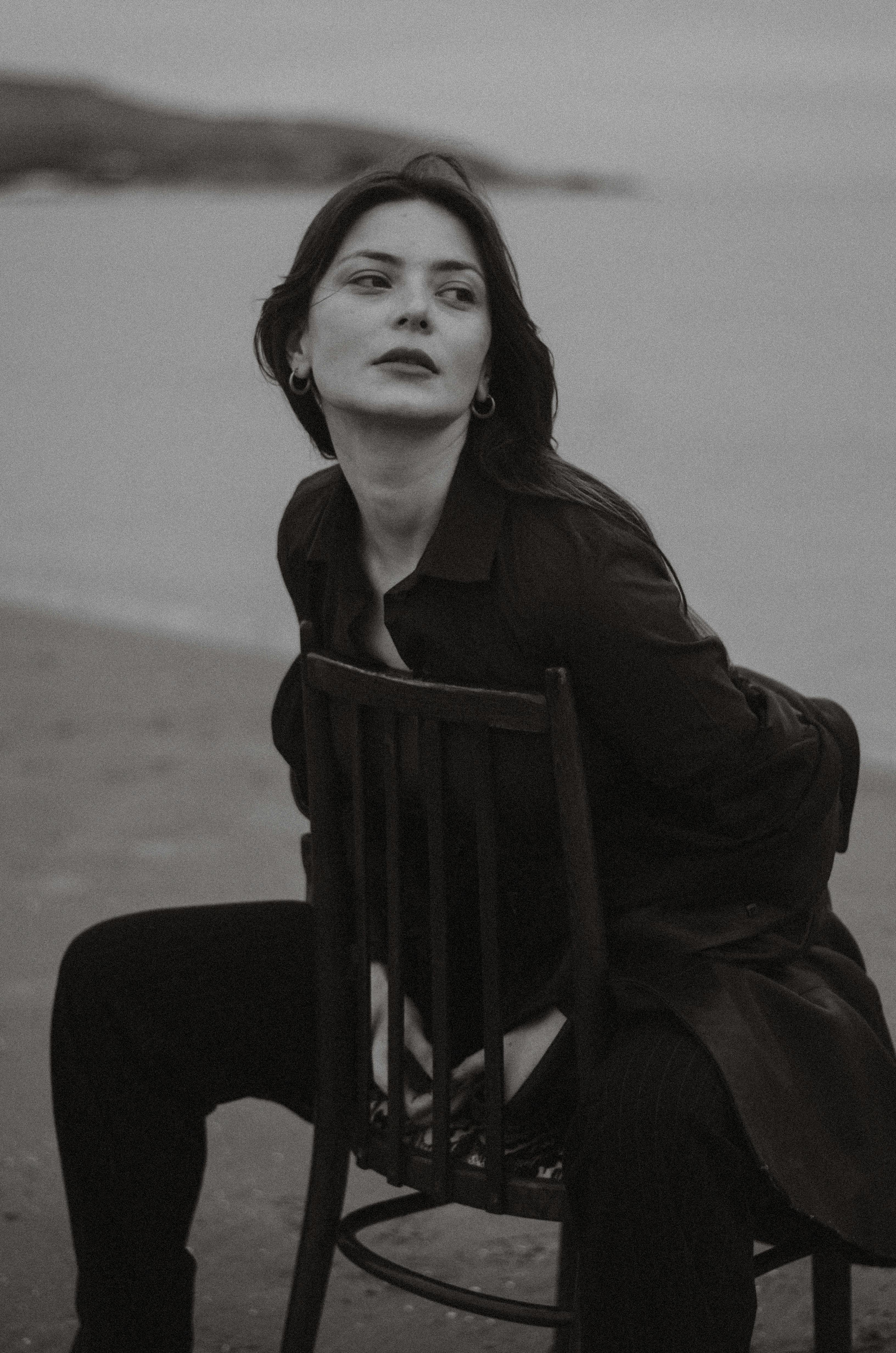 Black and white portrait of a woman sitting on a chair at the beach.