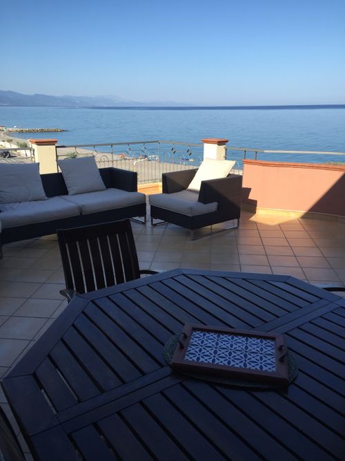 Free Relaxing seaside patio with modern furniture overlooking the ocean. Stock Photo
