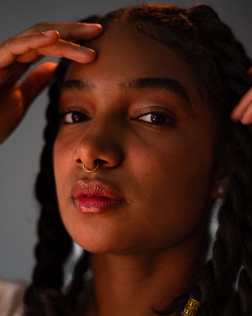 Free Vibrant close-up of a woman with braids and a nose ring exuding confidence. Stock Photo