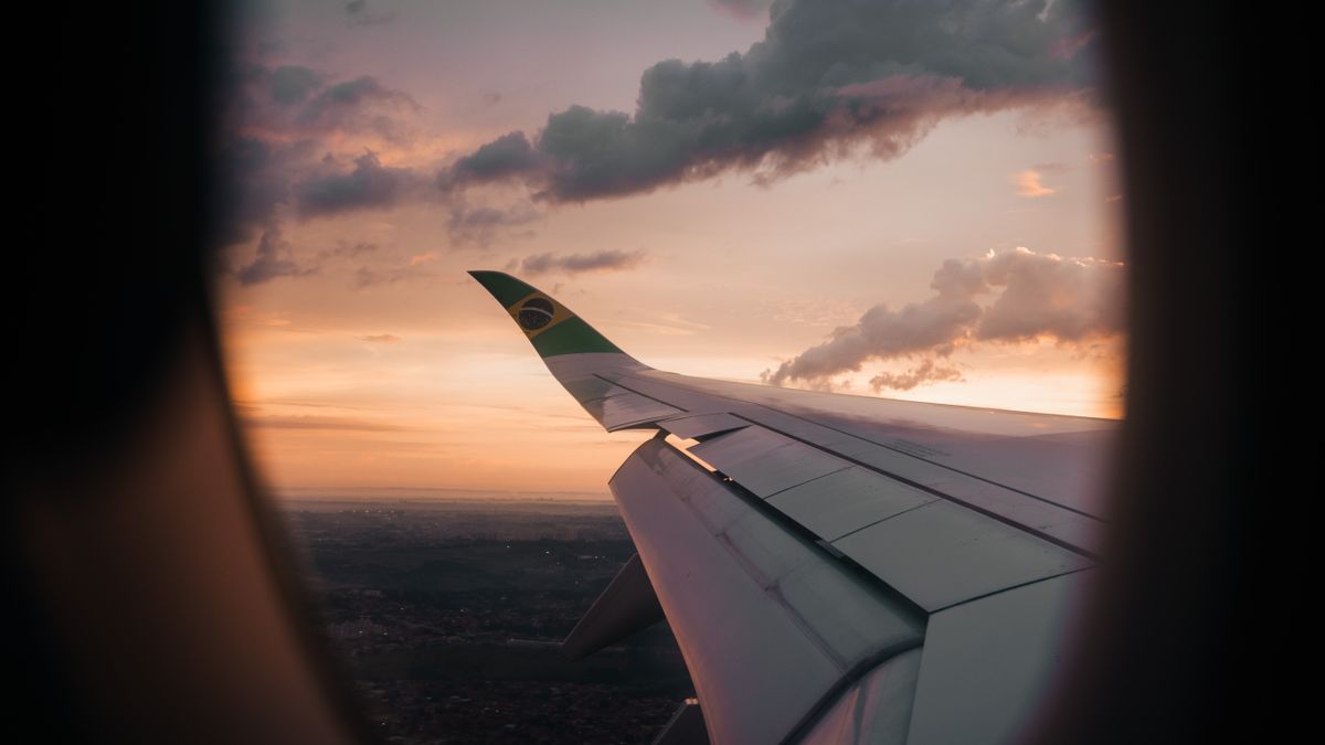 View from airplane window showing wing against a Brazilian sunset sky.