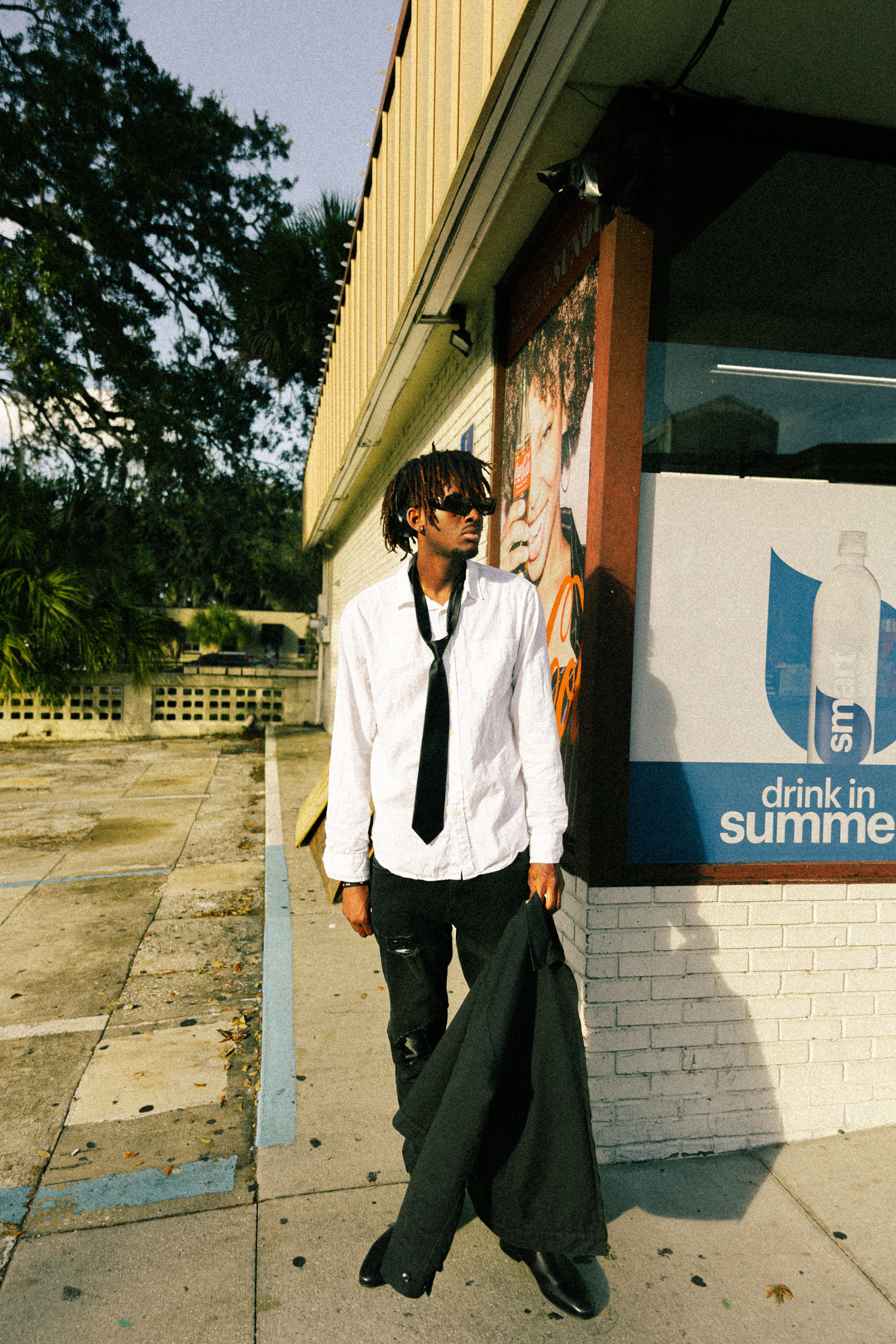 Stylish man in sunglasses posing outdoors in urban setting.