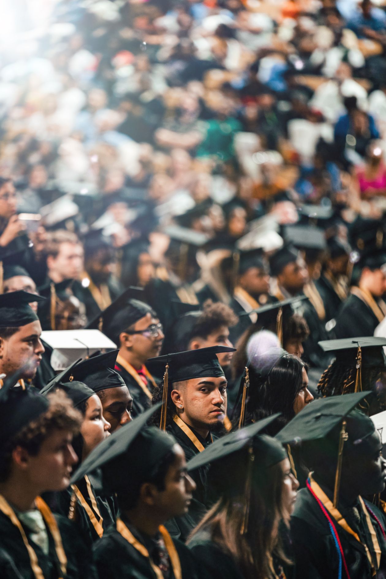 A crowd of graduates in caps and gowns celebrating at a commencement ceremony