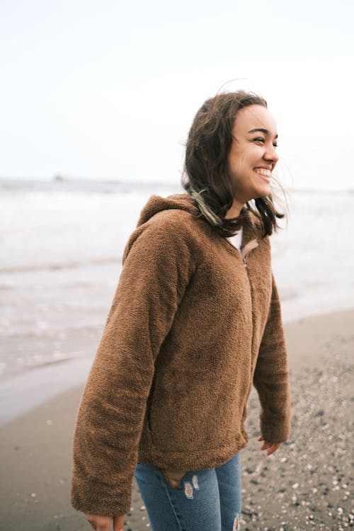 A Brunette Woman in a Brown Jacket on the Beach