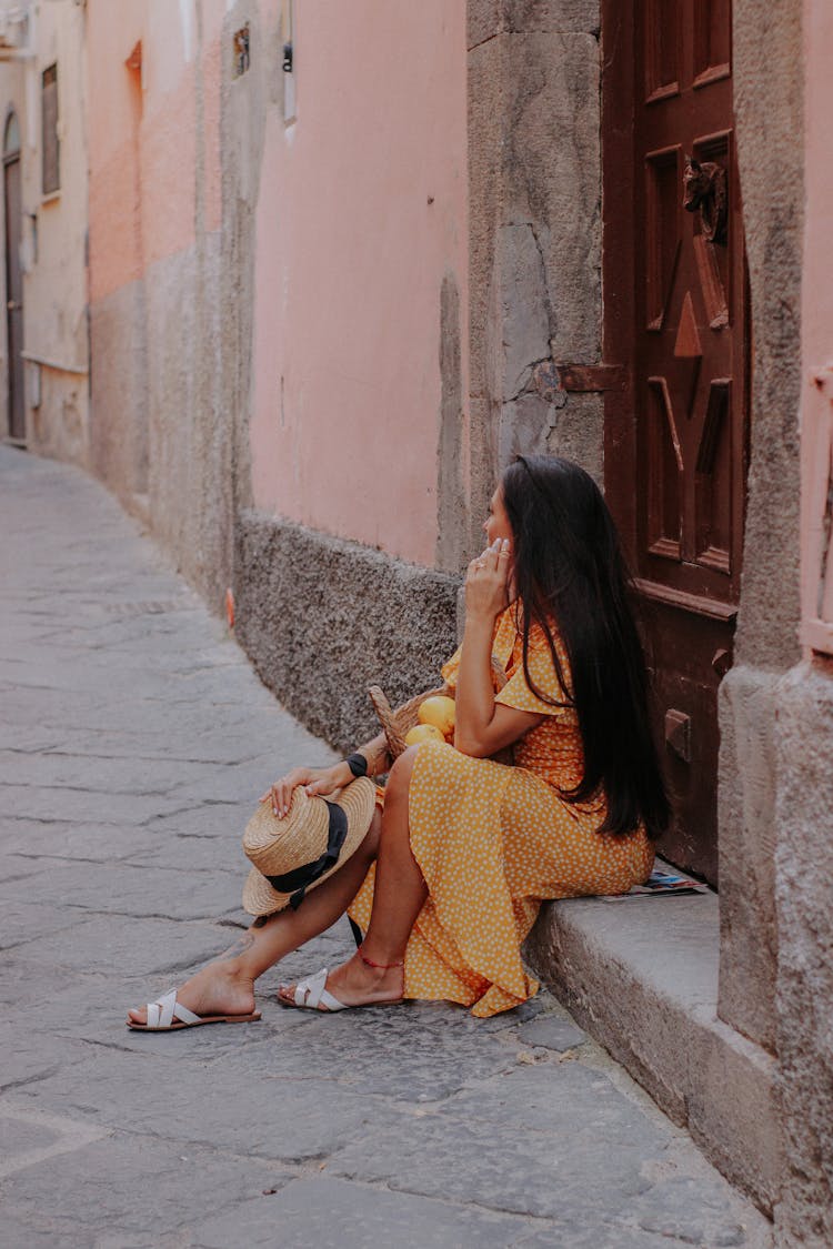 Woman Sitting On Step By Wooden Entrance Door