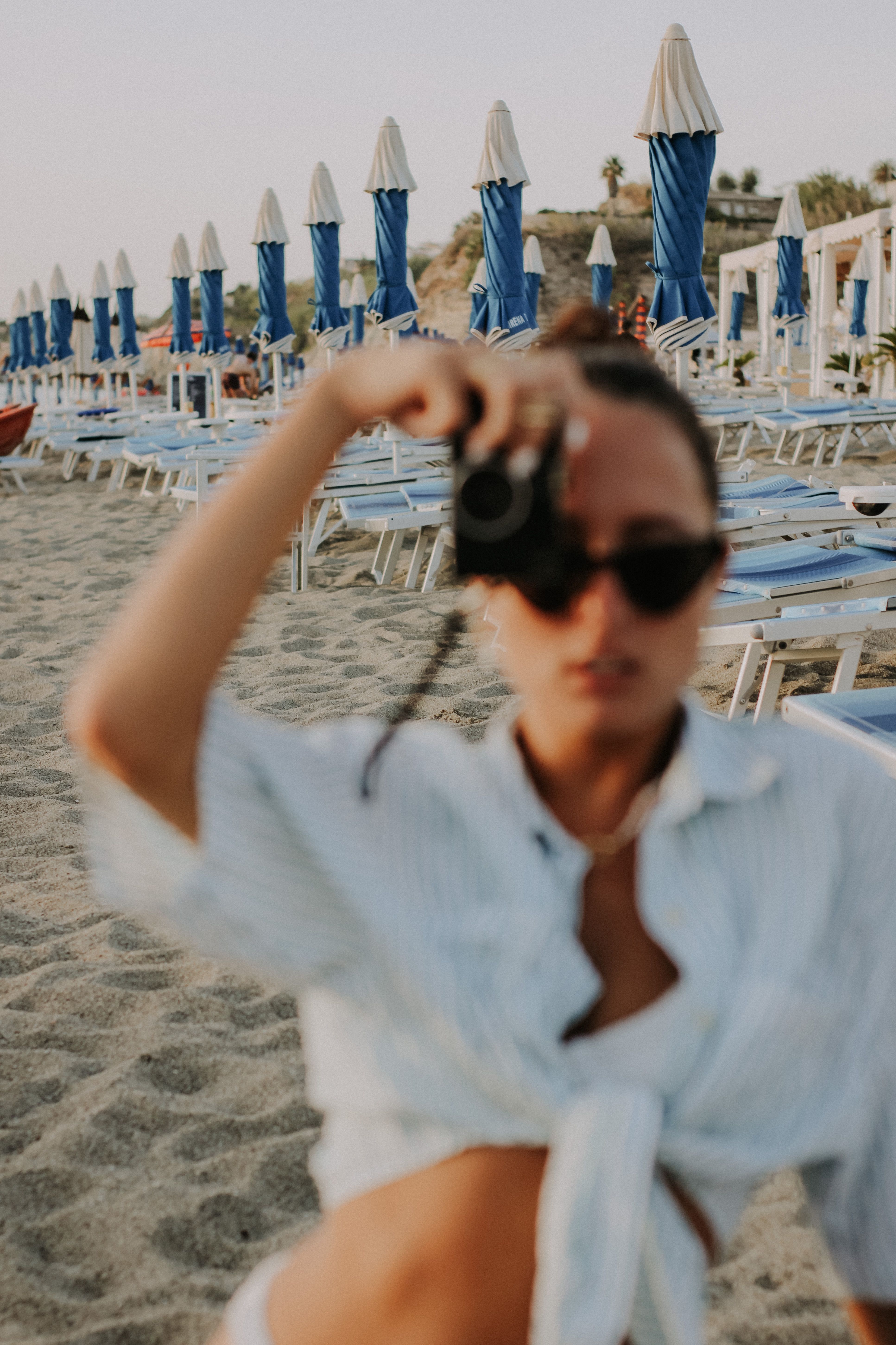 Defocused woman on a sunny beach taking photos. Perfect summer vacation backdrop.