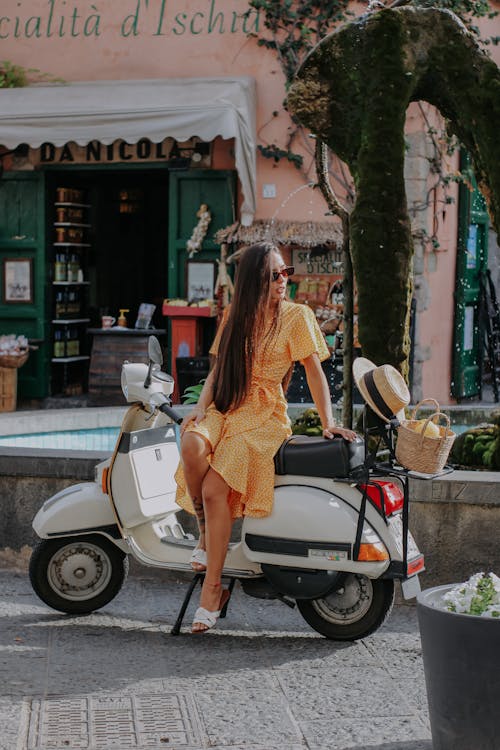 Young Brunette in a Dress Sitting on a Motor Scooter 
