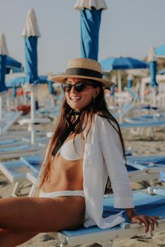 Fashionable woman in a bikini seated at a sunny beach resort, enjoying a summer day.