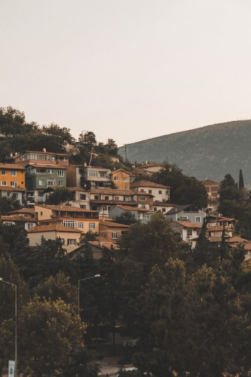 Free Scenic view of colorful hillside homes in Amasya, Türkiye, nestled among lush trees at sunset. Stock Photo